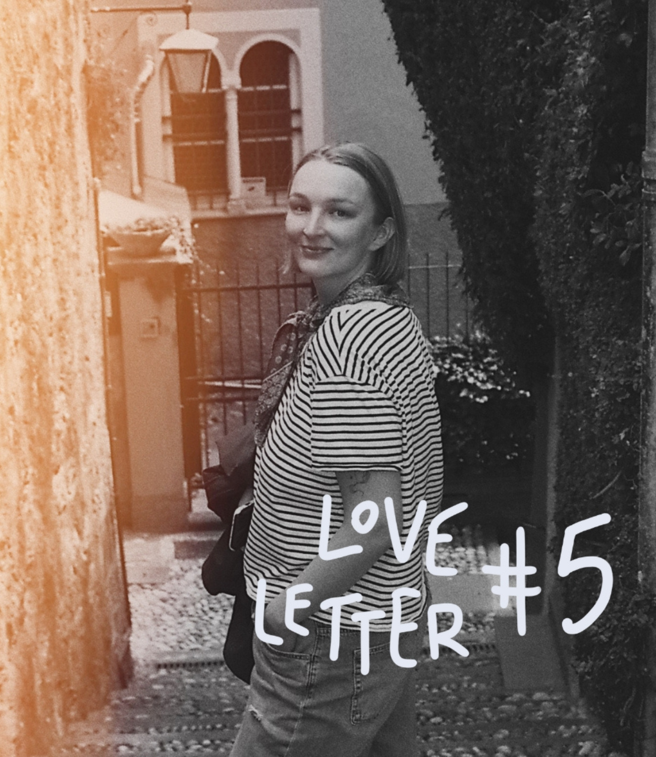 Woman in a picturesque alleyway looking directly into the camera over her shoulder